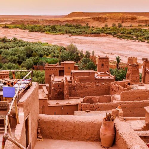 Discover Morocco's Enchanting Canyons and Valleys: a stunning view of the UNESCO World Heritage site of Ait Ben Haddou, a fortified village with a rich history dating back centuries., with its buildings and structures standing tall against the backdrop of a river.