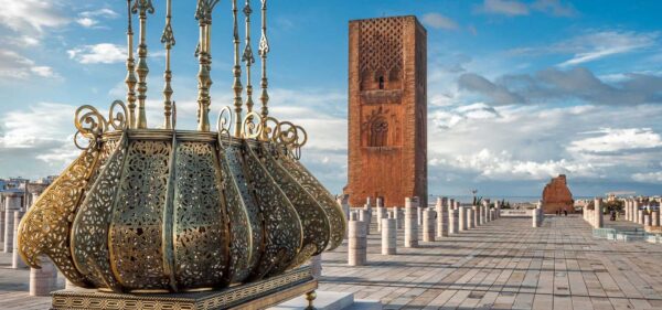 Imperial Cities Tour Islamic architecture. Traditional golden decorations with the emblem of Morocco. Tour Hassan Tower in a background with stone columns, Rabat Morocco.